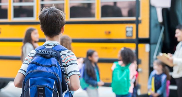 Young boy waits to load school bus