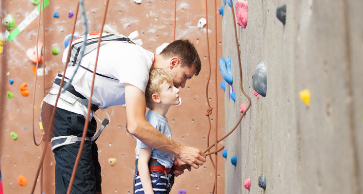 little boy preparing to climb rock wall