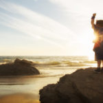 child at beach with hands up overcoming obstacles in life