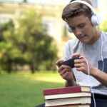 boy procrastinating by listening to music holding books