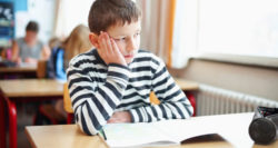 child at desk looking bored