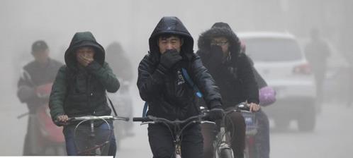People riding bikes in a Chinese city and covering their mouths because of the terrible air pollution