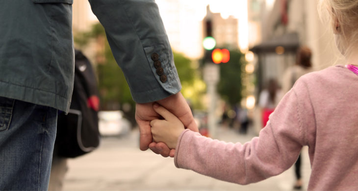 father holding daughters hand, walking to school