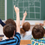children raising hands in school