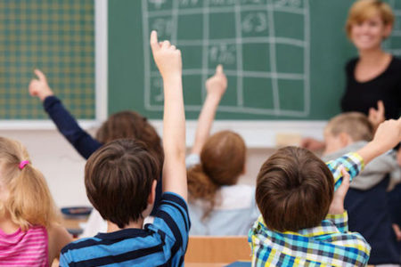 children raising hands in school