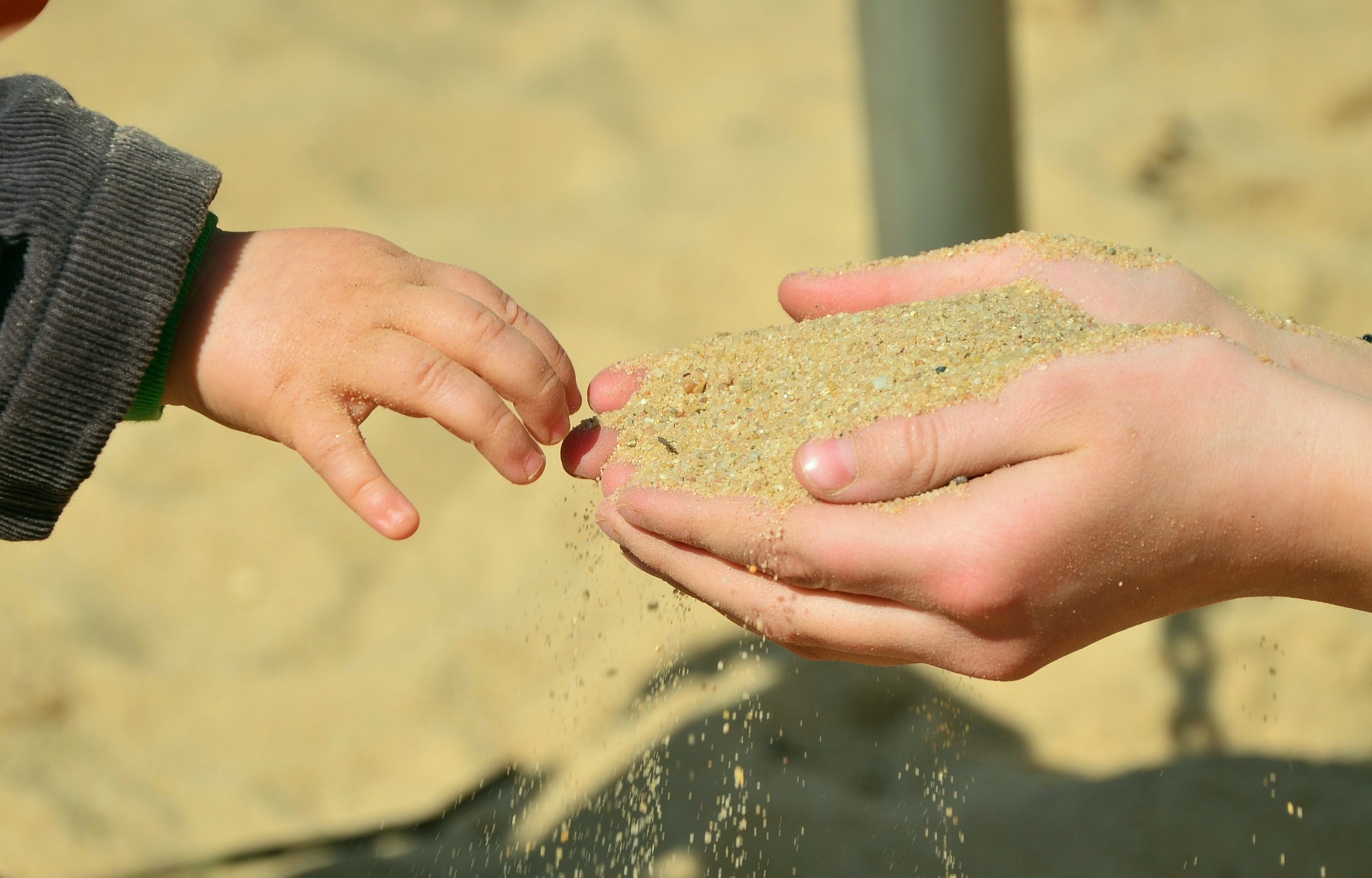 mother's hands holding out sand to child
