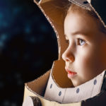 young girl in cardboard astronaut helment