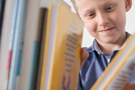 young boy looking at books on a bookshelf