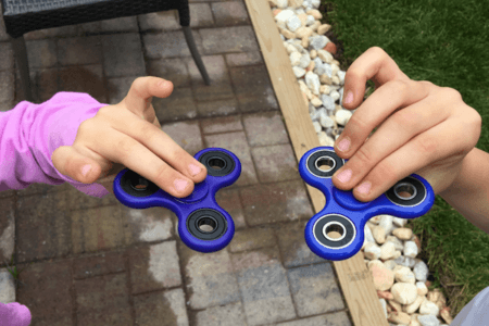 Child hands each holding a fidget spinner