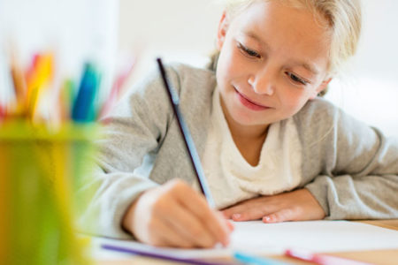 Child writing with pencil at desk