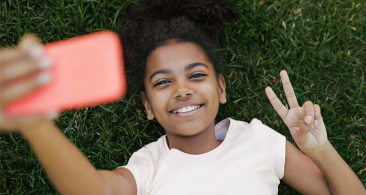 Smiling girl taking selfie on her smartphone
