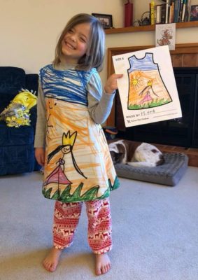 child holding artwork and wearing dress with same art