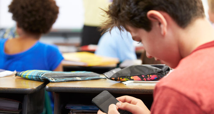 boy using smartphone in classroom
