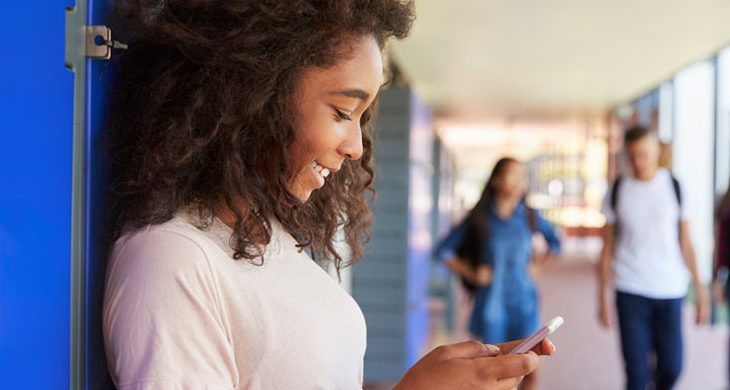 female student texting in school hallway
