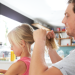 Father Styling Daughter's Hair At Breakfast Table