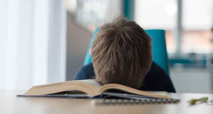 tired kid. resting head in open book on table