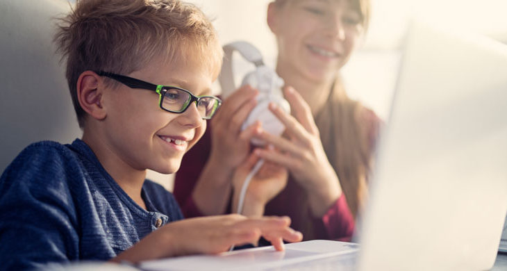 two kids laughing and looking at laptop