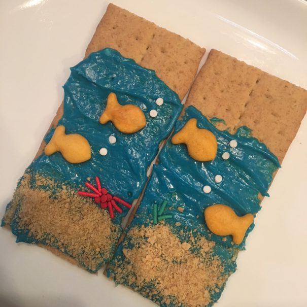 Graham crackers with blue icing, gold fish, and sprinkles