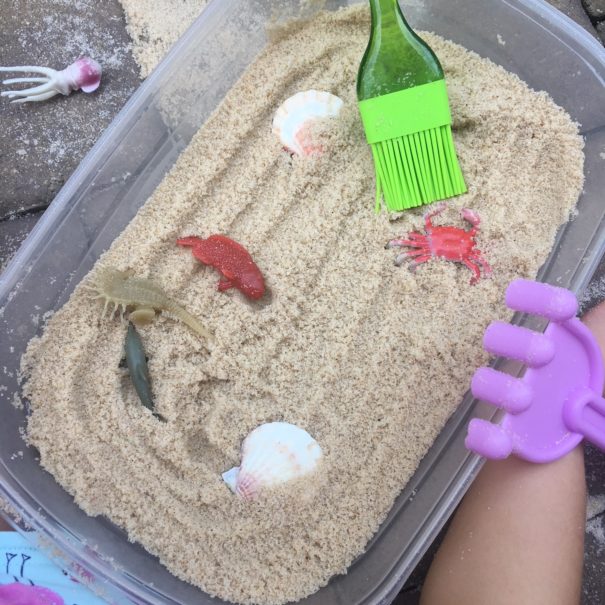 tupperware container with sand and plastic toys