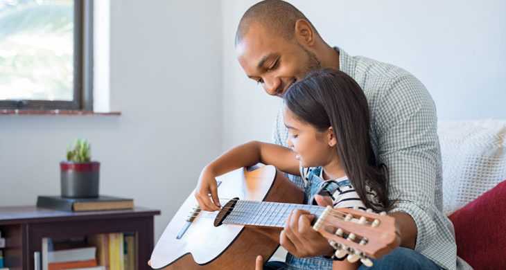 Father playing guitar with daughter