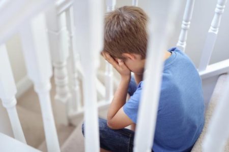 bullied child with head in hands sitting on stairs