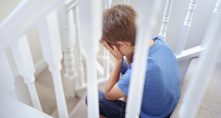 bullied child with head in hands sitting on stairs