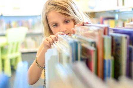 girl looking for a book in a library
