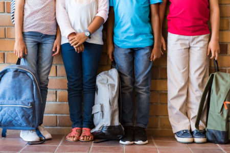 Children legs with backpacks at school
