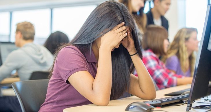 student with head in her hands at school desk