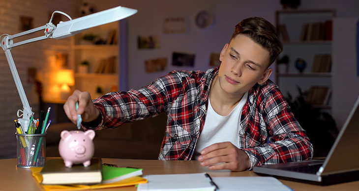 teen boy putting money in piggy bank