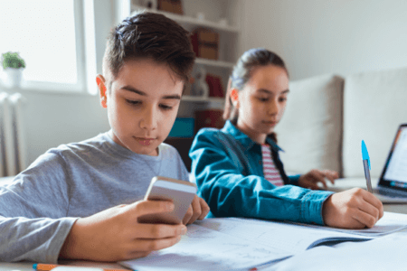 boy and girl independent learning on phone and laptop
