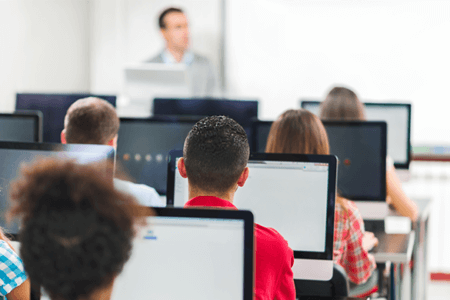 kids in a class with laptops on a desk