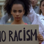 young girl holding No Racism sign