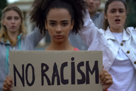 young girl holding No Racism sign